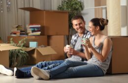 Happy couple moving home resting and talking sitting on the floor drinking coffee